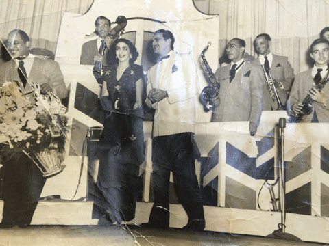 Dominican dancers Lucy Saladin and Papito Subrero receiving flowers from Josecito Roman, band leader of Orquesta Quisqueya at the Tropicana Club, 1950.
